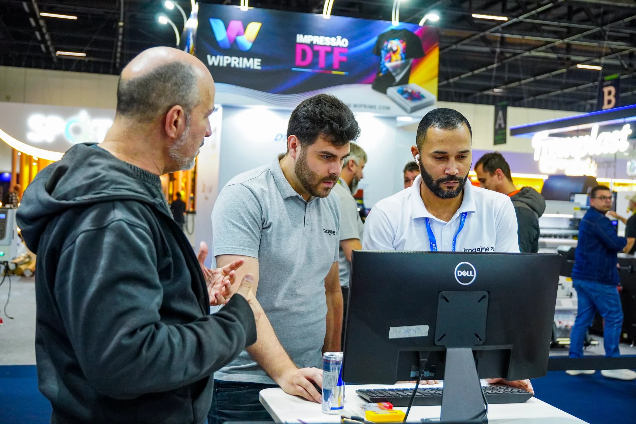 Equipe da Imagine PS e visitante reunidos diante de um computador durante uma feira